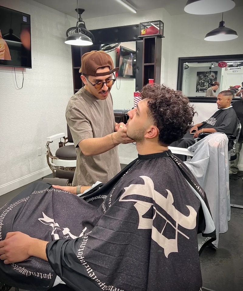 Barber trimming customer's beard in salon